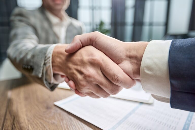Two,Businesspeople,Shake,Hands,Over,A,Document.,Their,Focused,Grip