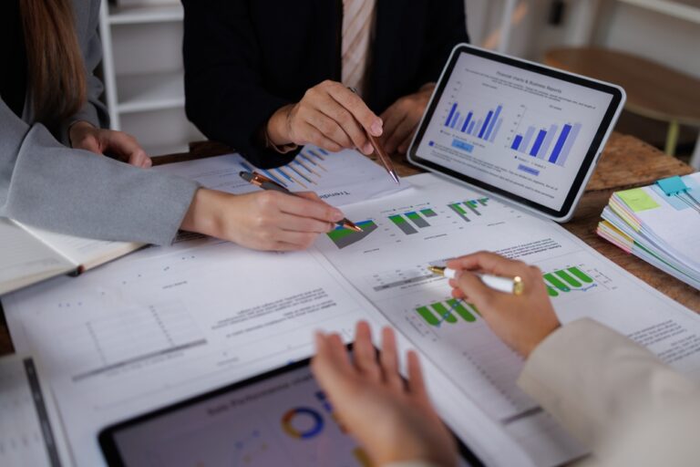 Business,People,Point,To,Graphs,And,Charts,To,Analyze,Market