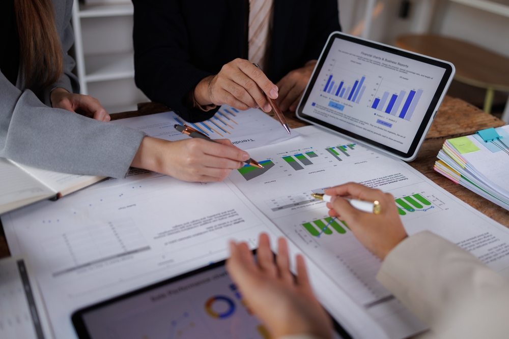 Business,People,Point,To,Graphs,And,Charts,To,Analyze,Market